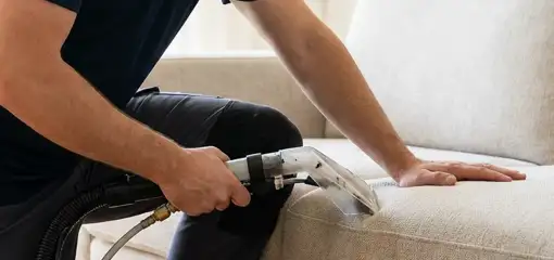 Professional upholstery cleaner deep-cleaning a fabric sofa with a handheld extraction tool, Newark, NJ.